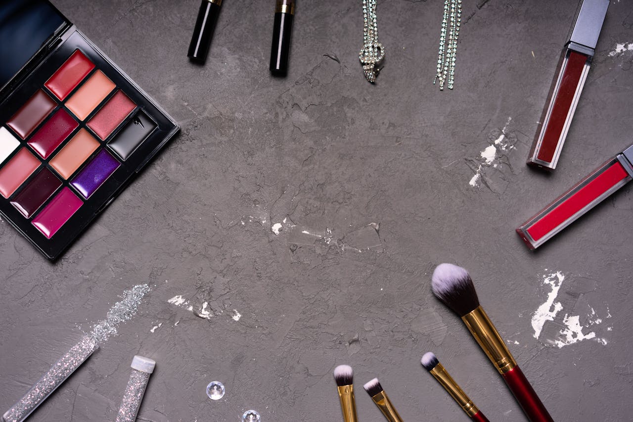 Stylish makeup arrangement featuring a diverse palette and brushes against a gray background.